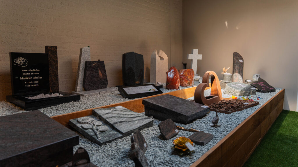 Liggende grafstenen en accessoires in de expositie